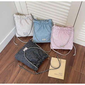 Flat lay of quilted chain handbags in blue, pink, grey and white on wood floor