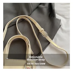 Détail de la bandoulière réglable en cuir beige avec boucle en métal argenté poli