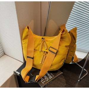 Detail of yellow nylon messenger bag featuring woven rope zipper pulls and plastic buckle