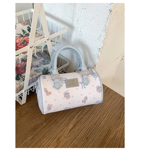 Close-up of printed Boston bag with metal logo plate, animal patterns and blue handles