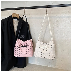 Détail de sacs seaux matelassés avec petits nœuds, grand nœud décoratif et pendentif cœur