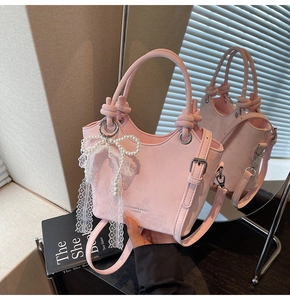Détail du sac seau rose avec nœud perlé et pendentif en dentelle sur cuir nubuck