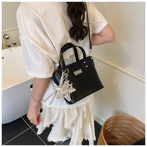 Detail of black crocodile pattern bucket bag with large silver star charm decoration