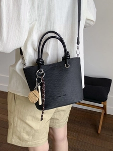 Black textured leather small tote bag with sports charm and adjustable shoulder strap