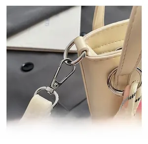 Gros plan détaillé du crochet métallique argenté et des coutures sur le sac seau beige