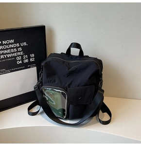 Detail of black nylon travel backpack showing the transparent PVC pocket and durable straps