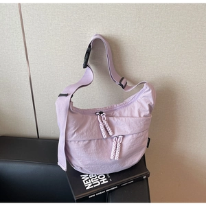 Detail of lavender nylon crescent bag with woven zipper pulls and wide strap