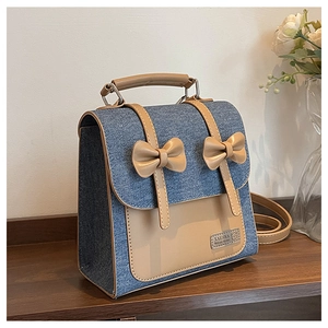 Detail of vintage denim backpack featuring leather bows and metallic brand plaque