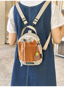 Detail view of mini drawstring crossbody bag with orange plaid pattern and tennis racket charm