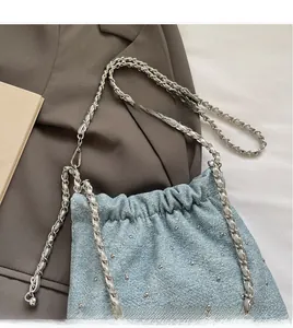 Detail of light blue denim bucket bag featuring silver studs and quilted chain strap