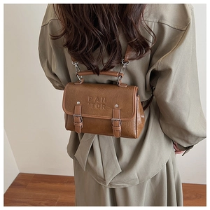 Rear view of a model wearing a brown vintage leather backpack with dual metallic buckles