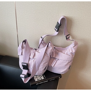 Detail of light purple nylon crossbody bags with woven zipper pulls and adjustable straps