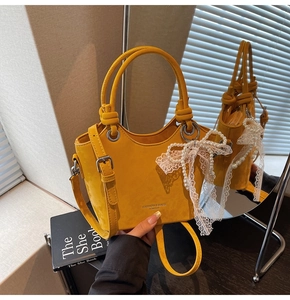 Détail du sac seau en cuir jaune avec bandoulière perle, nœud dentelle et lettrage