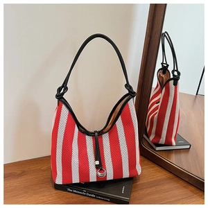 Detail of red and white striped mesh tote bag with black leather strap on a wooden desk