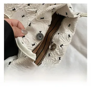 Détail du fermoir magnétique argenté et doublure rayée du sac seau blanc texturé