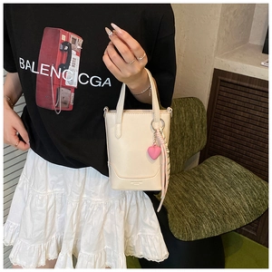Détail du mini sac seau blanc cassé avec breloque cœur et décoration en foulard