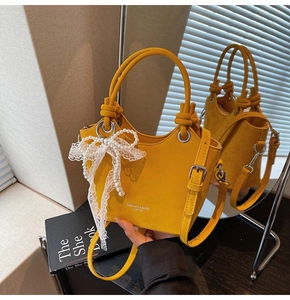 Détail du sac seau en cuir jaune avec nœud en dentelle perlée et boucle argentée