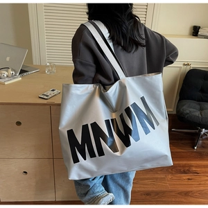 Detail of silver metallic tote bag with black MNWM lettering in a cozy office setting