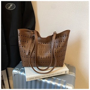 Détail d'un sac cabas en cuir marron avec des motifs géométriques évidés découpés au laser