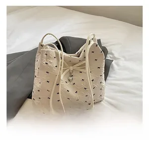Détail du sac fourre-tout crème avec volants, imprimés nœuds et pendentif cœur