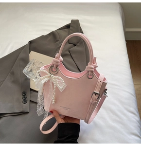 Détail du sac seau rose orné d'un nœud en dentelle et de perles élégantes