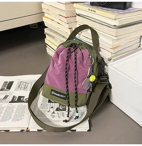 Detail of crossbody bag with purple grid pattern, drawstring closure and tennis keychain