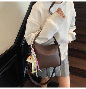 Détail du sac seau en cuir grainé marron foncé avec un pendentif arc-en-ciel coloré