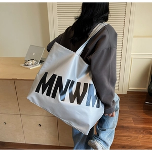 Detail of silver metallic tote bag with black MNWM lettering worn by a model