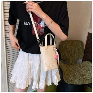 Détail du sac seau crème avec pendentif cœur rose et ruban en soie sur mannequin