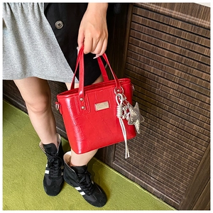 Detail of red crocodile texture handbag with star charm and silver woven tassels