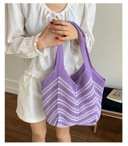 Dettaglio della borsa tote in maglia a onde viola e bianche tenuta da una modella