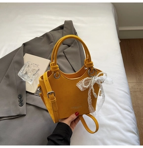 Détail du sac cabas jaune avec pendentif perle sur fond de veste de costume grise