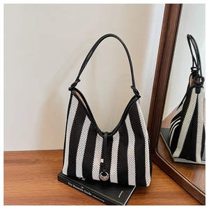Close-up of black and white striped woven tote bag with leather trim and silver ring buckle