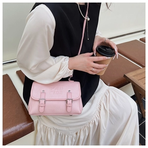 Close-up of light pink PU leather crossbody bag with silver buckles and embossed logo