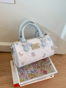 Mini Boston bag with cartoon bear print and blue trim displayed on vintage books
