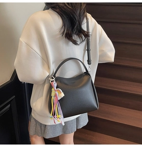 Détail du sac seau noir en cuir foulonné porté par un mannequin avec pendentif arc-en-ciel