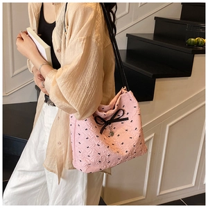 Détail du sac cabas plissé rose avec motifs nœuds noirs et pendentif cœur argenté