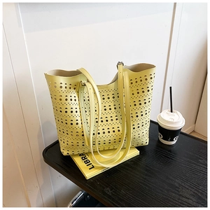 Détail du sac cabas jaune découpé au laser avec motifs ajourés sur un banc noir