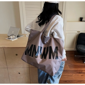 Detail of taupe large capacity shoulder tote bag with MNWM lettering and matte texture