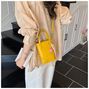 Sac seau jaune vif agrémenté d'un foulard en soie et d'un pendentif cœur rose