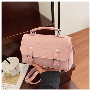 Detail of pink lychee leather texture with PAN TOR embossed logo and metallic buckles