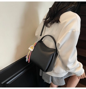 Vue détaillée d'un sac seau en cuir grainé noir avec pendentif arc-en-ciel sur modèle