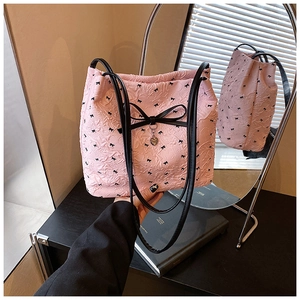 Détail du sac seau plissé rose avec nœuds noirs et pendentif en métal en forme de cœur