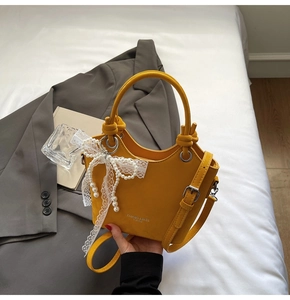 Détail du sac seau en cuir PU jaune avec dentelle blanche et pendentif nœud en perles