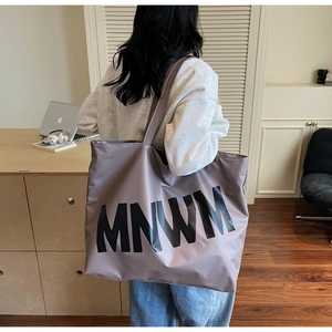 Spacious taupe tote bag with MNWM lettering shown in a modern lifestyle setting