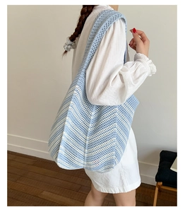 Dettaglio della borsa tote in maglia a righe blu e bianche con texture all'uncinetto e caduta