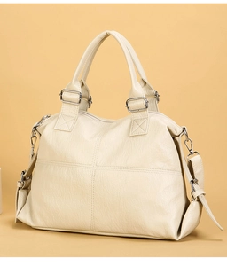 Detail shot of a cream leather tote bag featuring cross-stitching and adjustable strap