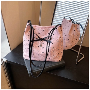 Détail du sac fourre-tout rose à texture gaufrée avec nœuds noirs et pendentif cœur