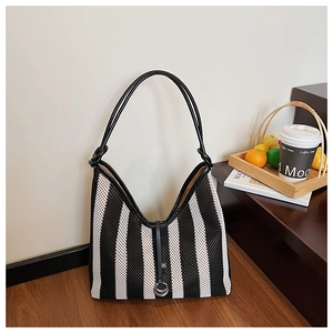 Detail of black and white striped woven tote with leather strap and metal ring