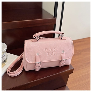 Detail of pink pleated faux leather bag with PANTOR logo on a wooden surface
